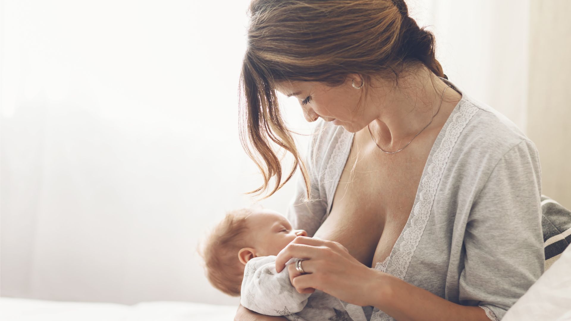 Madre amamantando a su bebé en un ambiente tranquilo e iluminado con luz natural, reflejando la conexión entre la lactancia y el bienestar emocional.